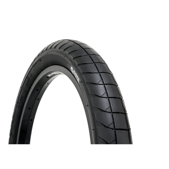 Close-up of the Fly Bikes Fuego 20 Inch Tyre, a black street riding tire featuring a tread pattern of rectangular grooves, displayed against a plain white background. Engineered for pinch-flat resistance and high pressure puncture protection, this tire delivers durability and reliability for urban road use.