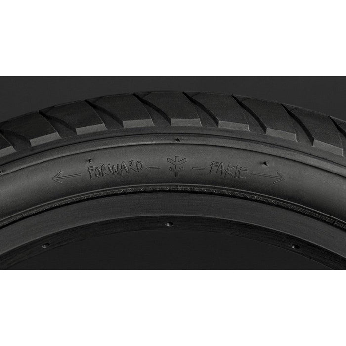 Close-up of the Fly Bikes Fuego 20 Inch Tyre showcasing its tread pattern and directional markings labeled “FORWARD” and “FAKE,” with arrows pointing in opposite directions. This tyre’s high-pressure, puncture-resistant construction helps prevent pinch-flats, making it an excellent choice for urban cyclists.
