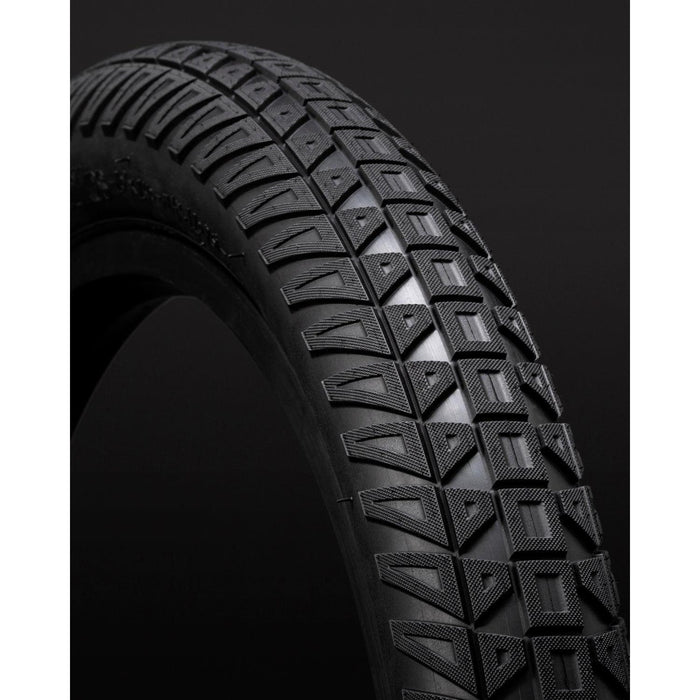 Close-up of a BMX tyre with distinct tread against a dark background: the Fly Bikes Ruben Tyre Ligera STD showcases its detailed surface, enhanced by HPPR layer technology for optimal performance.