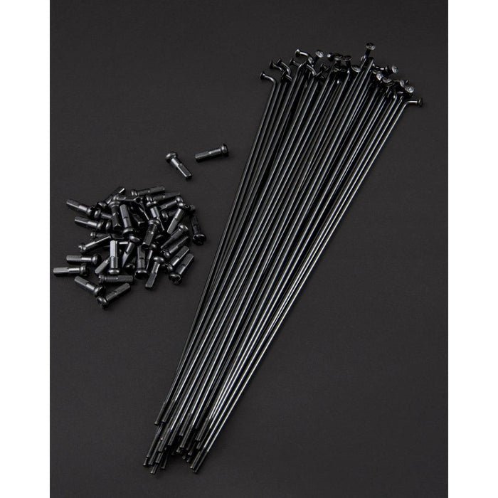 Fly Bikes Spokes (20 Pack) in black and stainless steel nipples are displayed on a dark surface, highlighting the precision of high-tension lacing.